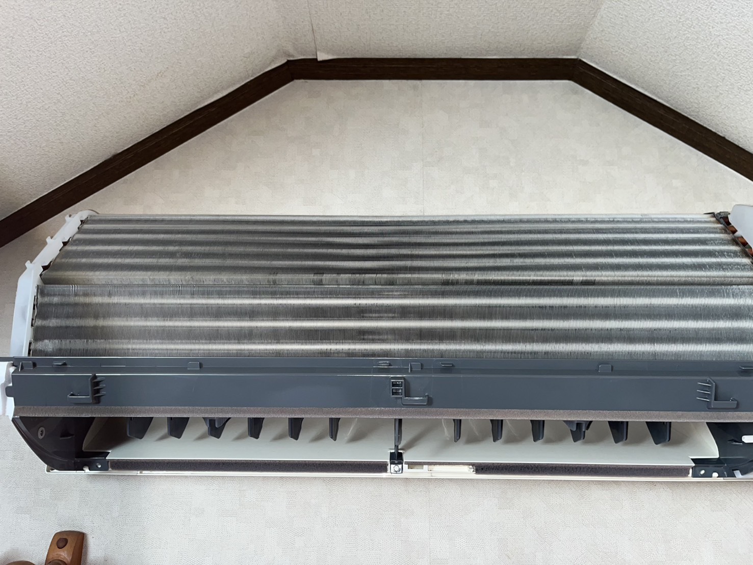 カバーを外したエアコン室内機。熱交換器のフィンと吹き出し口が見え、吹き出し口下部の黒い点状の付着物が目立たない状態