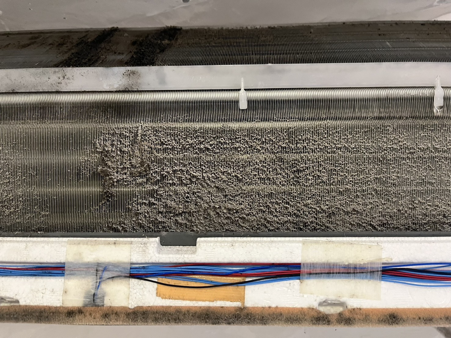 熊谷市での分解洗浄前、エアコン室内機の熱交換器フィンに灰色の付着物と黒い塊状の付着物が見える様子